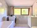 Campus, Forschung, Karriere: Attraktives Dachgeschoss-Appartement in Planegg - Helles, gefliestes Badezimmer mit großem Fenster und Badewanne